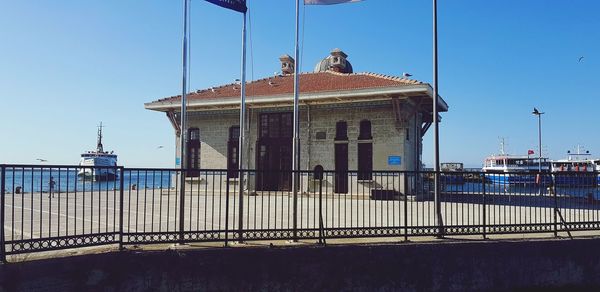 Built structure by sea against clear blue sky