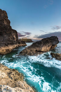 A rugged cornish coastal landscape with waves flowing at sunset with motion blur and dramatic skies