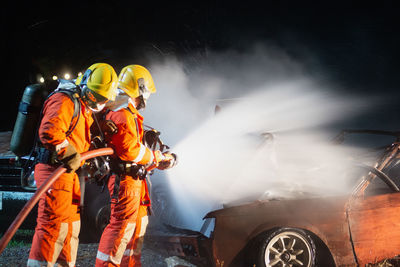 Firefighters extinguishing fire on car