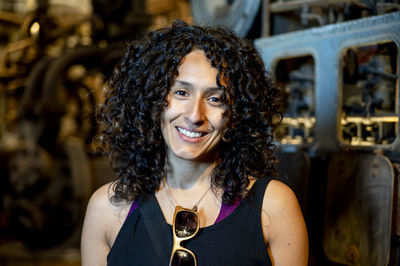 Portrait of a mixed race woman smiling while posing inside an abandoned factory.