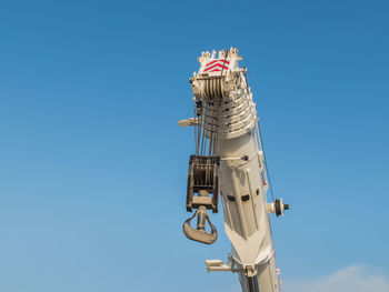 Low angle view of crane against clear blue sky