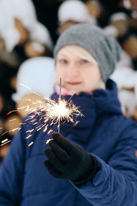 Portrait of young woman holding sparkler in park