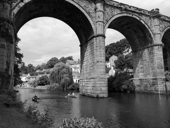 Arch bridge over river in city against sky
