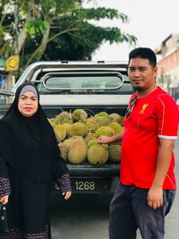 Portrait of smiling family standing against fruits in vehicle