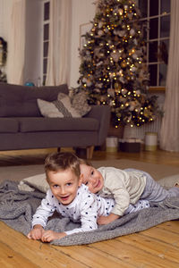 Two brothers in pajamas having fun on new year's eve next to the tree