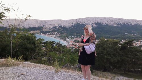 Smiling woman standing on mountain against sky