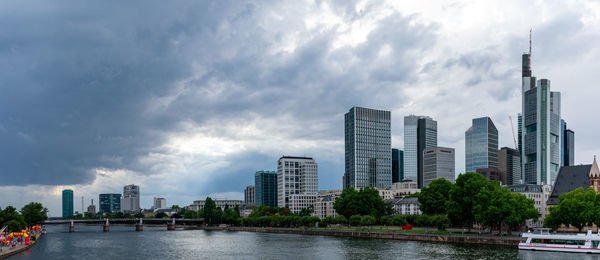 Modern buildings by river against sky