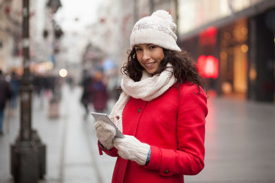 Young woman using mobile phone on street during winter