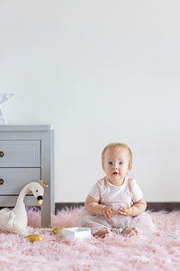 Little caucasian baby girl ten months old playing with wooden toys at home or nursery. 