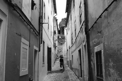 Man walking on cobblestone street amidst buildings