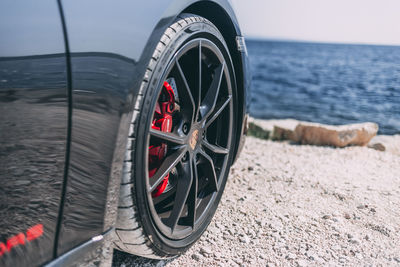 Close-up of wheel by sea against sky