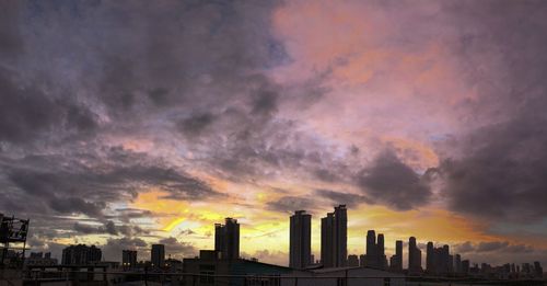 Scenic view of buildings against dramatic sky during sunset