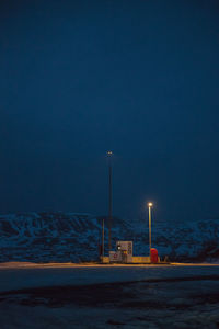 Illuminated street light by sea against clear sky at dusk