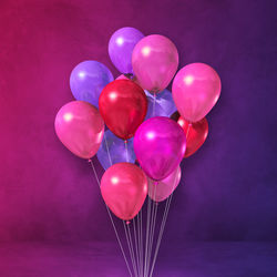 Close-up of multi colored balloons against pink background