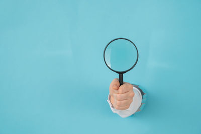 Woman's hand holding a magnifying glass on a blue background