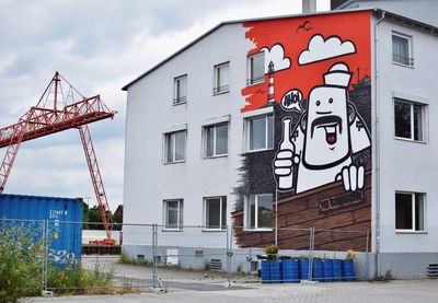 Graffiti on building by street against sky