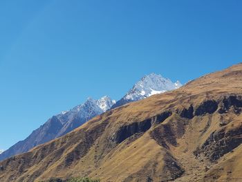 Scenic view of snowcapped mountains against clear blue sky