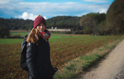 Woman wearing hat standing on field during winter