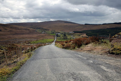 Empty road along landscape against sky