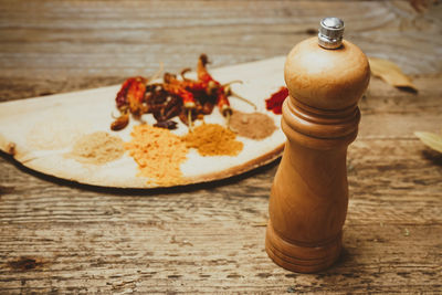 Wooden pepper mill by spices on table