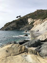 Rock formations on beach against sky