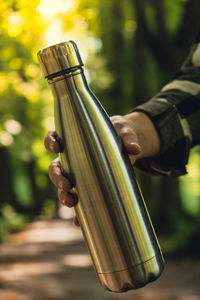 Close-up of unrecognizable female hand holding water bottle. reusable steel thermo water bottle in