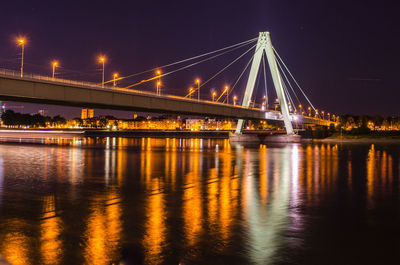 Illuminated bridge over river against sky in city at night