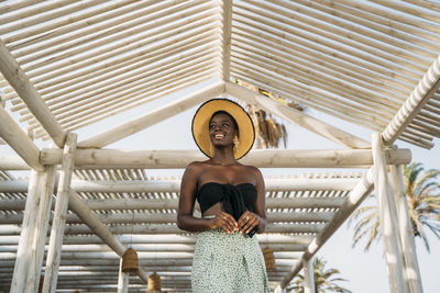 Young woman smiling while standing under wooden covered roof