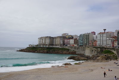 Buildings by sea against sky