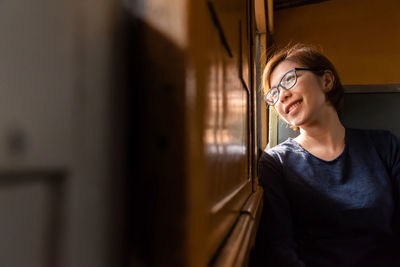 Mid adult woman looking away through window while sitting in train