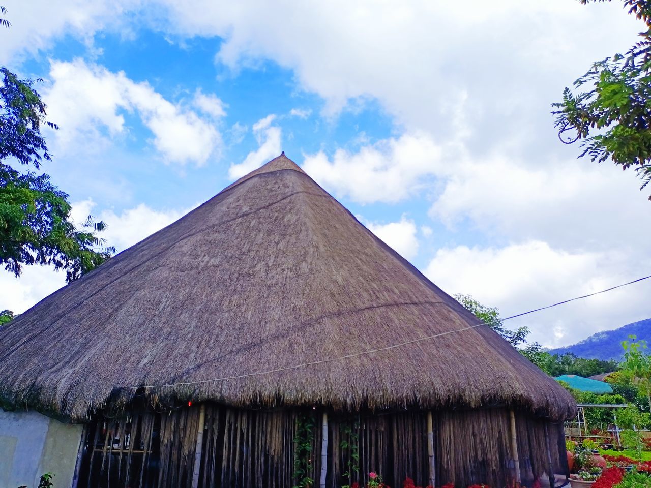 thatched roof, roof, thatching, architecture, sky, cloud, built structure, hut, nature, building exterior, building, plant, house, no people, landscape, travel destinations, rural area, outdoors, land, tree, travel, beauty in nature, day, tradition, mountain, rural scene, environment, tourism, village, scenics - nature