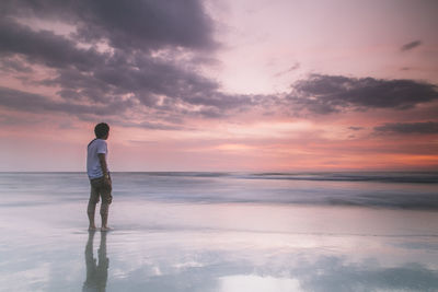 Man standing at beach during sunset