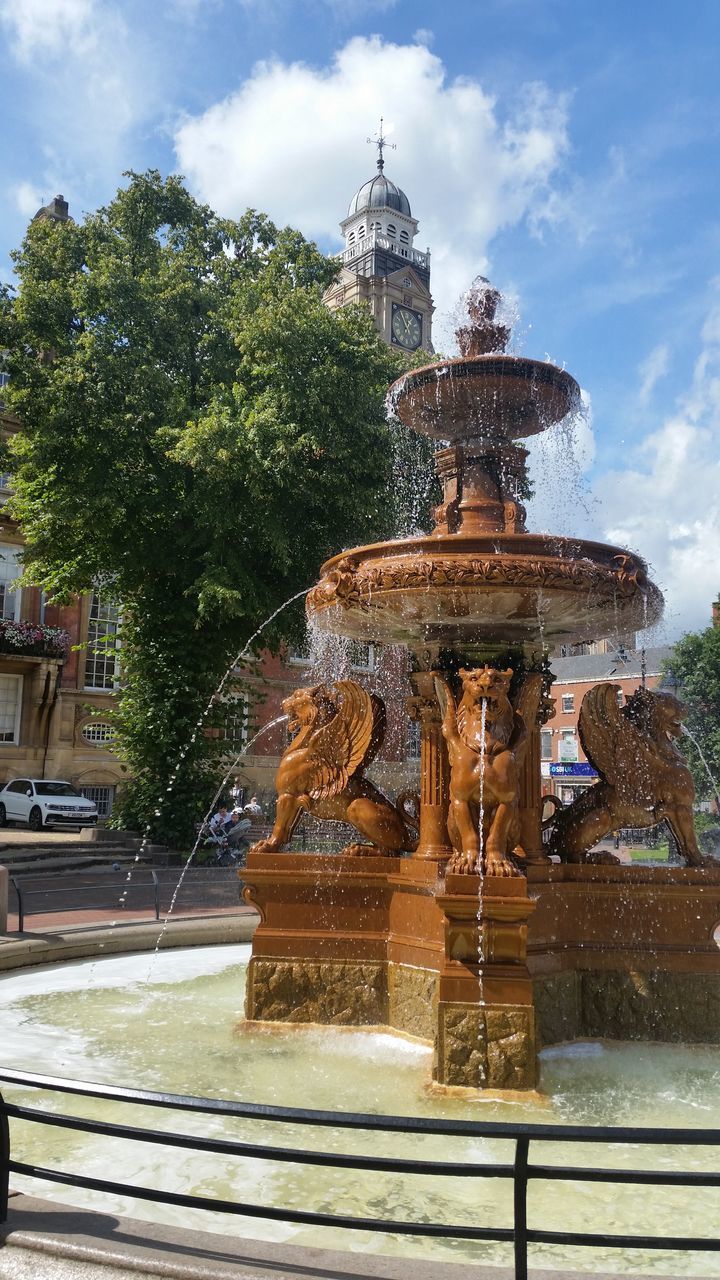 STATUE BY FOUNTAIN AGAINST BUILDING