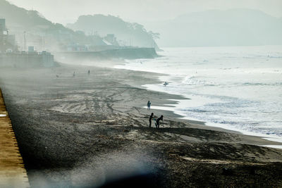 People on beach against mountains