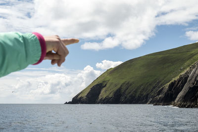 Midsection of person by sea against sky