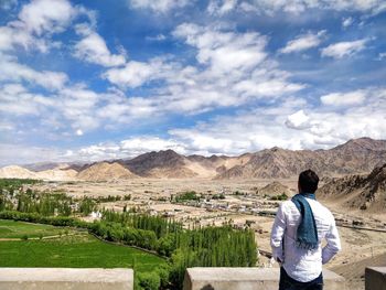 Rear view of man standing on mountain against sky