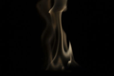 Close-up of burning candle against black background