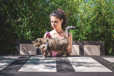 Woman with dog sitting against plants