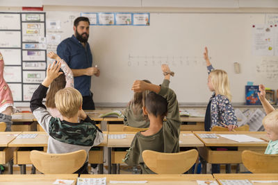 Children raising hands classroom