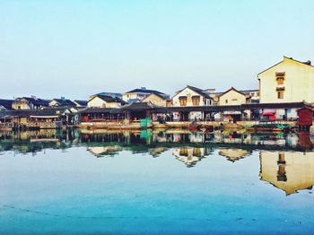 Buildings by lake against blue sky