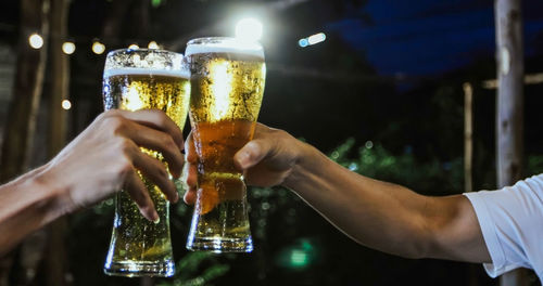 Cropped hands of friends toasting beer glasses