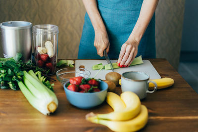 An unrecognizable housewife cuts ingredients for a healthy lunch on the board. 