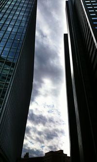 Low angle view of modern buildings against cloudy sky