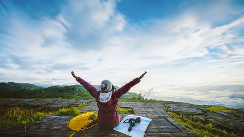 Rear view of woman doing yoga on mountain against sky