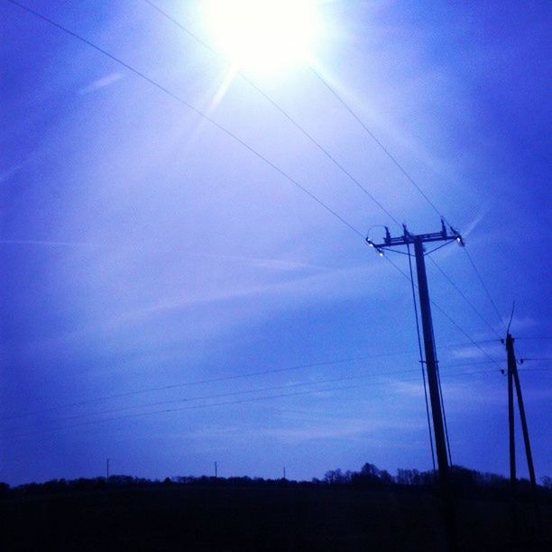 fuel and power generation, electricity, electricity pylon, power line, power supply, technology, connection, low angle view, blue, cable, silhouette, sun, vapor trail, tranquility, sky, sunlight, tranquil scene, nature, beauty in nature, sunbeam