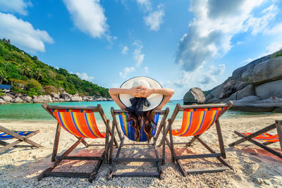 Deck chairs on beach against sky