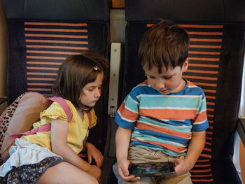 Two siblings watching a movie in a smartphone in a train