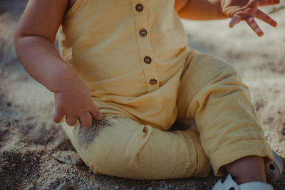 Midsection of baby girl sitting at beach