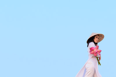 Low angle view of woman standing against blue sky