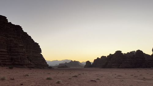 Rock formations on landscape against clear sky during sunset